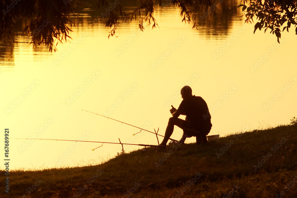Fisherman with fishing rods in the evening at sunset.