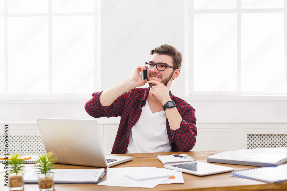 Young satisfied businessman has a mobile talk in modern white office Young satisfied businessman has a mobile talk in modern white office