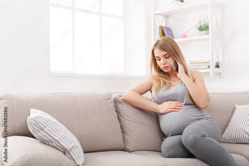 Worried pregnant woman talking on phone copy space Worried pregnant woman talking on phone copy space