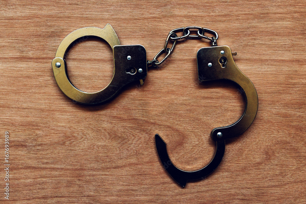 Handcuffs on wooden background Handcuffs on wooden background