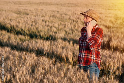 Female farmer in wheat field talking on mobile phone