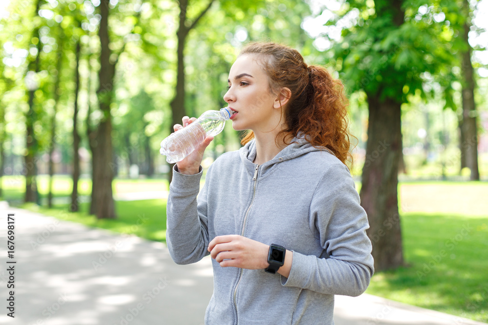 Woman runner is having break, drinking water Woman runner is having break, drinking water