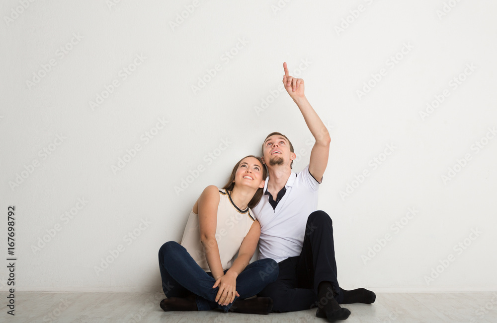 Obraz premium Couple looking up, sitting on floor