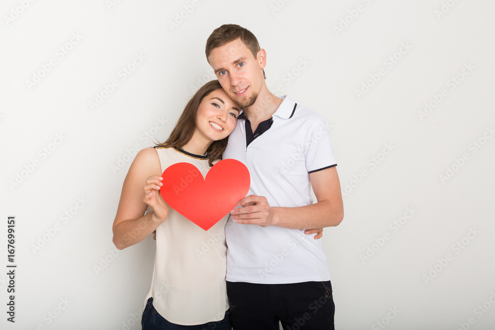 Young happy couple in love holding red paper heart Young happy couple in love holding red paper heart