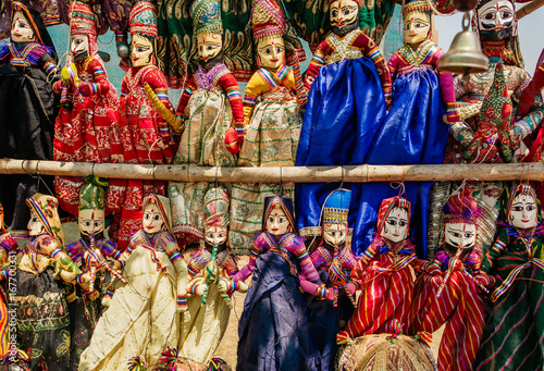 Souvenir toys of traditional Indian market. Faces of funny handmade dolls in old costumes for children in Asia