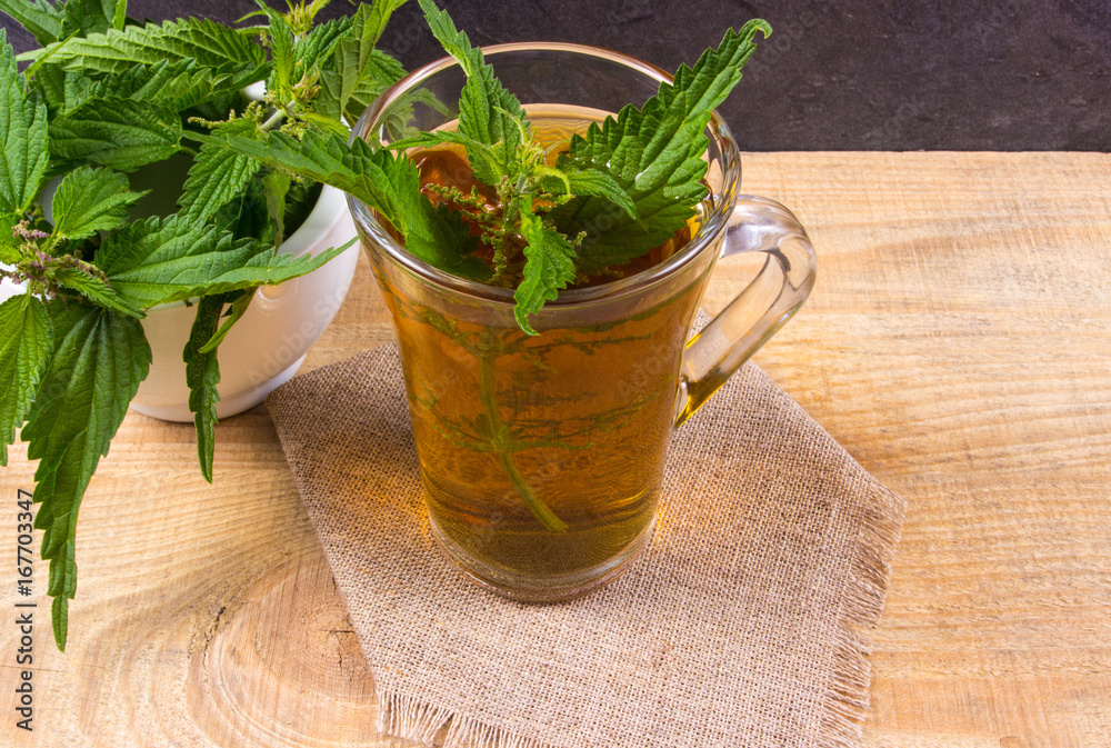Healing tea with nettle. Tea in a glass cup on a wooden table. The source of vitamins.