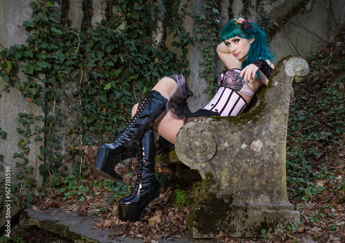 Young beautiful pin up glamour girl with green color hair, high boots on old stone vintage garden photo