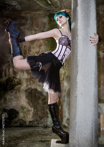 Young beautiful pin up glamour girl with green color hair, high boots on old stone vintage garden photo