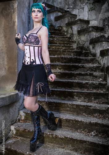 Young beautiful pin up glamour girl with green color hair, high boots on old stone vintage stairs photo