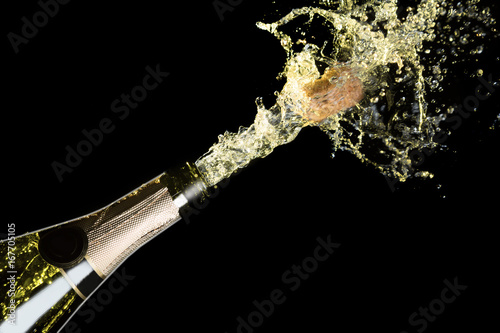 Celebration theme with explosion of splashing champagne sparkling wine on black background.