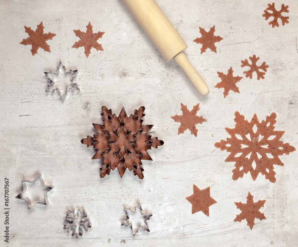 Gingerbread dough and the metallic snowflake on white table, top view, cooking background Gingerbread dough and the metallic snowflake on white table, top view, cooking background