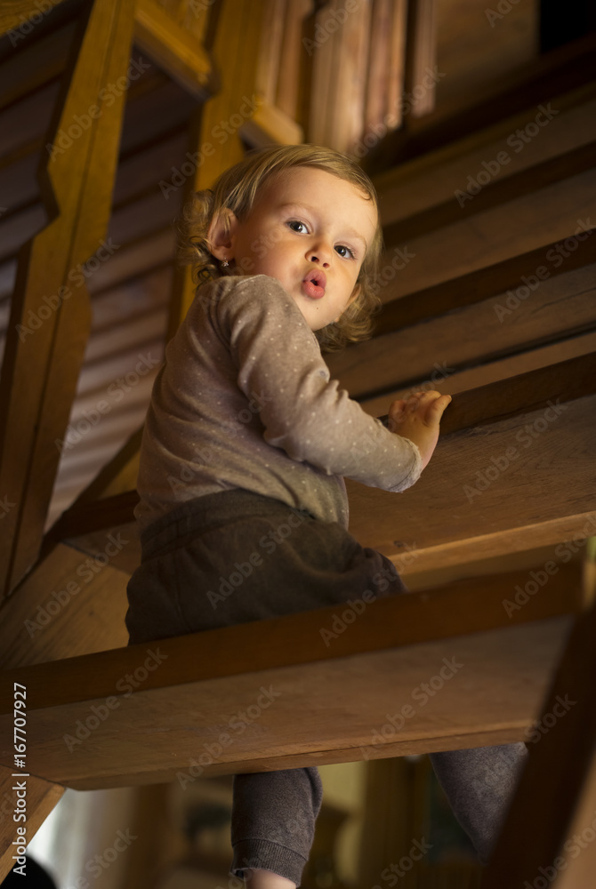 Surprised child sitting on wooden stairs Surprised child sitting on wooden stairs