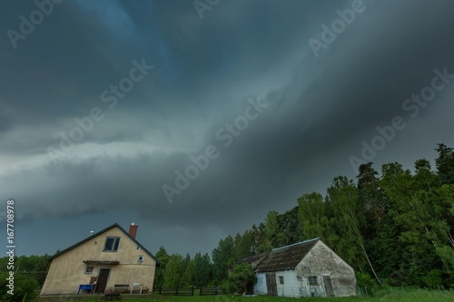 Scarry dark storm clouds over forest and house © milosz_g