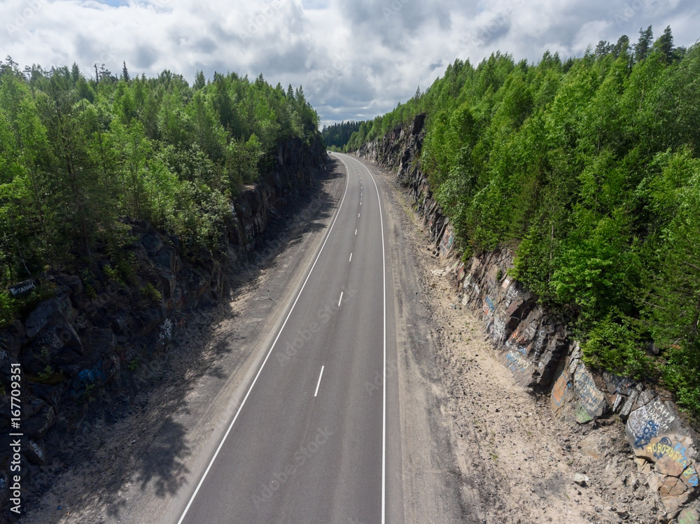 Country two lane highway is between rocks, aerial view