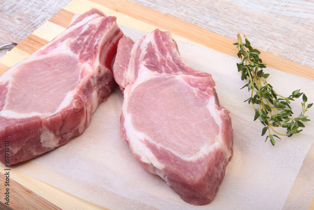 Raw pork chops, spices and rosemary on cutting board. Ready for cooking. Raw pork chops, spices and rosemary on cutting board. Ready for cooking.