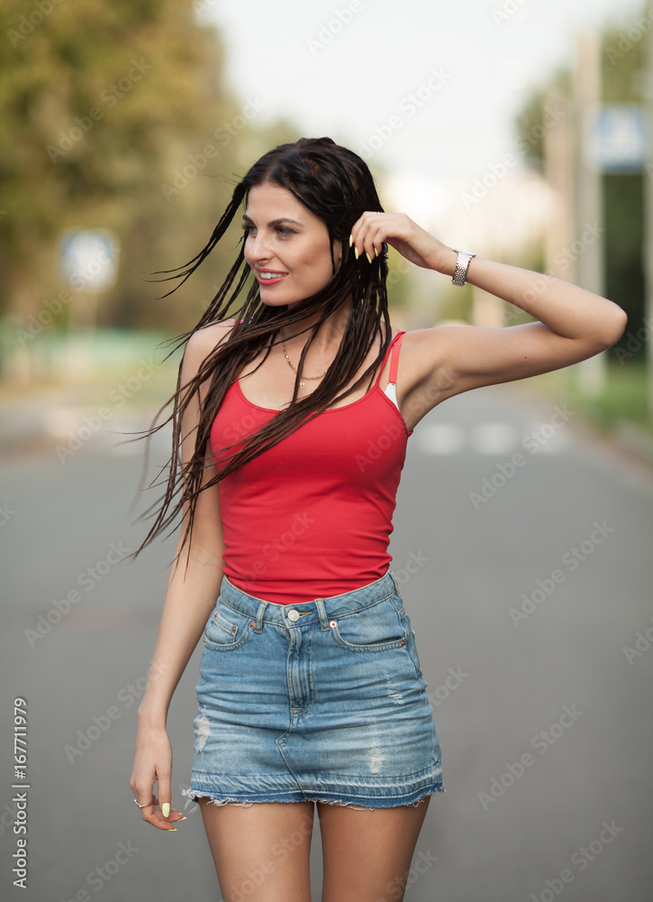 Young beautiful and sexy girl with slim sun tanned attractive body dressed  in jeans skirt is posing outdoor in the summer city. Woman with trendy  pigtails Stock Photo | Adobe Stock