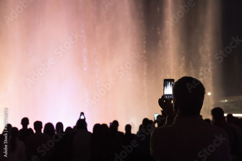 Man take a photo of the light and music fountain show. Dancing water