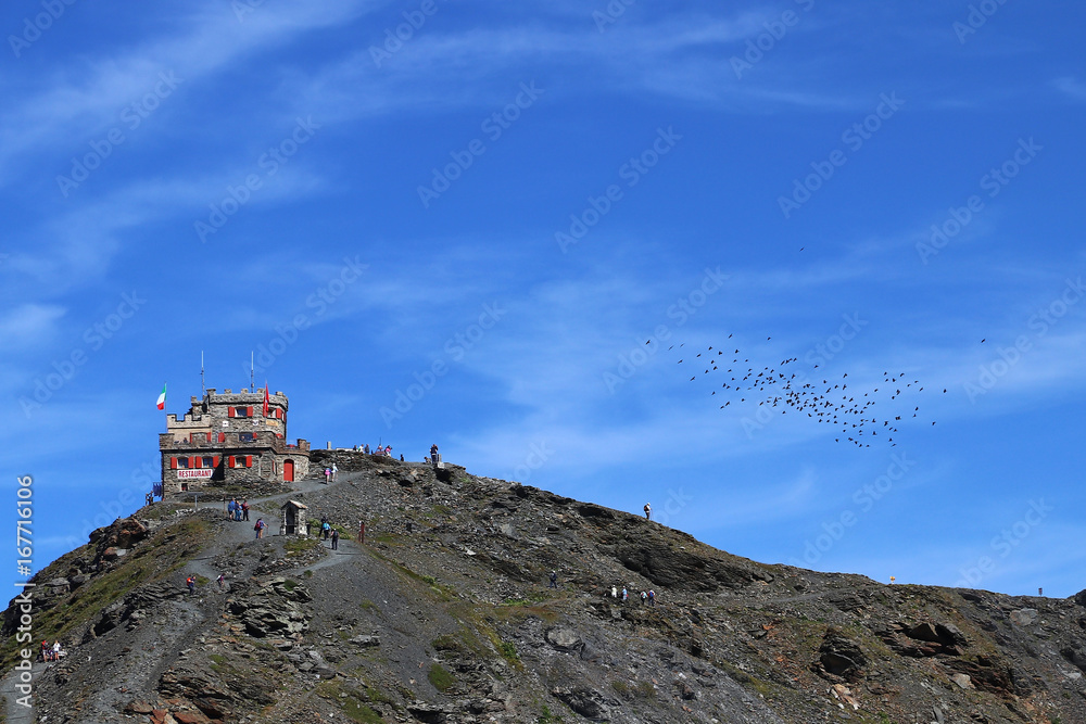 Ein Restaurant hoch oben im Gebirge mit einem Schwarm Vögel Ein Restaurant hoch oben im Gebirge mit einem Schwarm Vögel