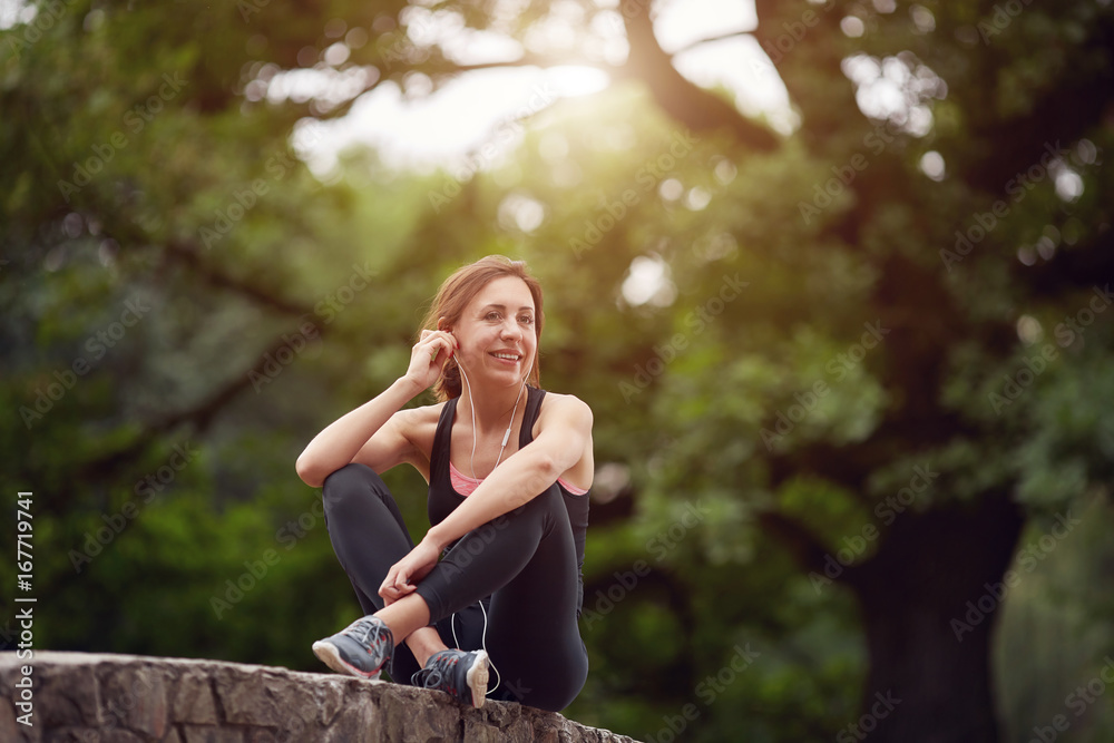 Naklejka premium Cheerful sportswoman with headphones in park