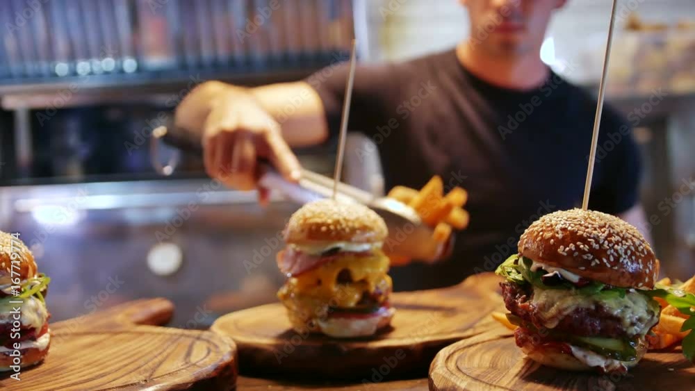 A young cook lays out delicious French fries in an American hamburger