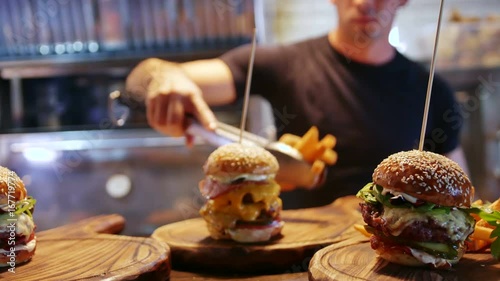 A young cook lays out delicious French fries in an American hamburger