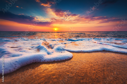 Beautiful sunrise over the sea and washing waves on the sand
