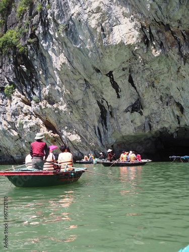 Tourist bamboo boats heading to the cave beneath the cliff in Ha long bay, Vietnam