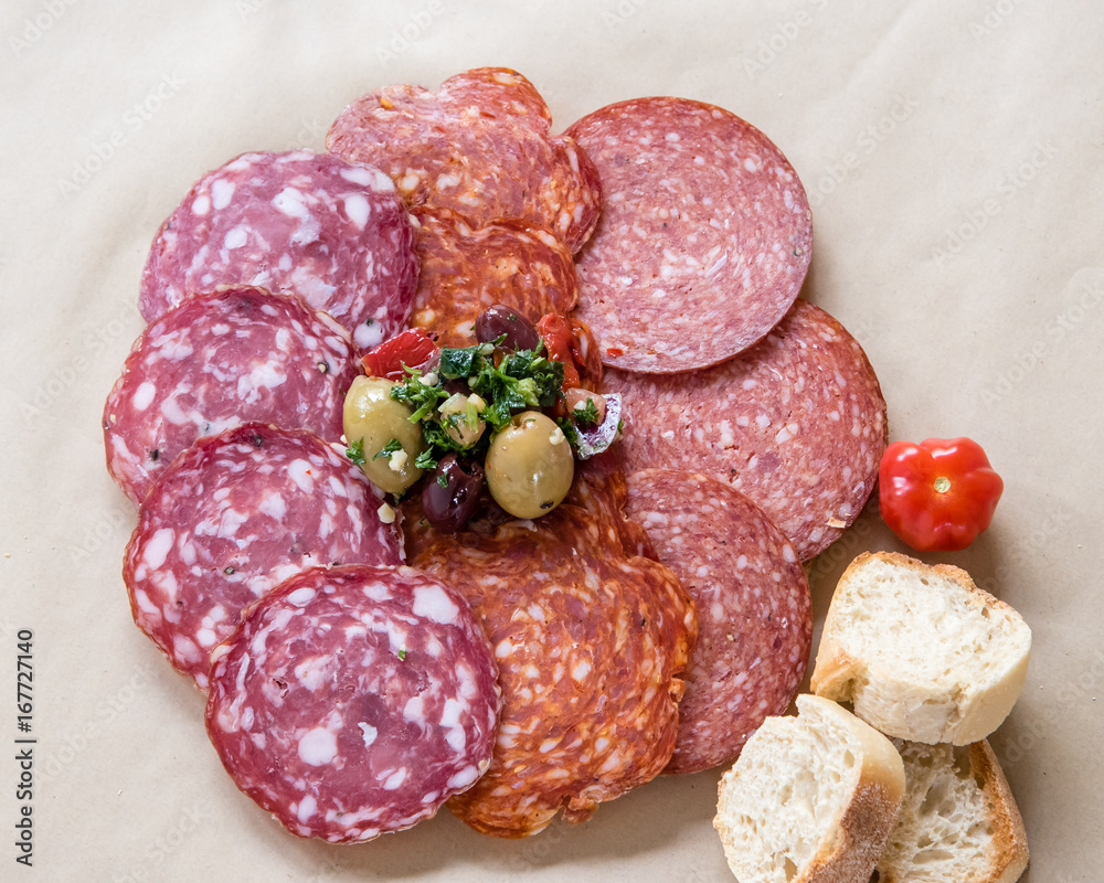 Salami rosette with slices of bread garnished olives. Plate of antipasti appetizers, sliced salami and sausage with bread and olives. Salami rosette with slices of bread garnished olives. Plate of antipasti appetizers, sliced salami and sausage with bread and olives.