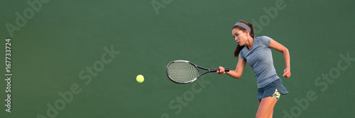 Tennis player Asian woman playing hitting ball on court banner. Copy space panorama crop on green background. © Maridav