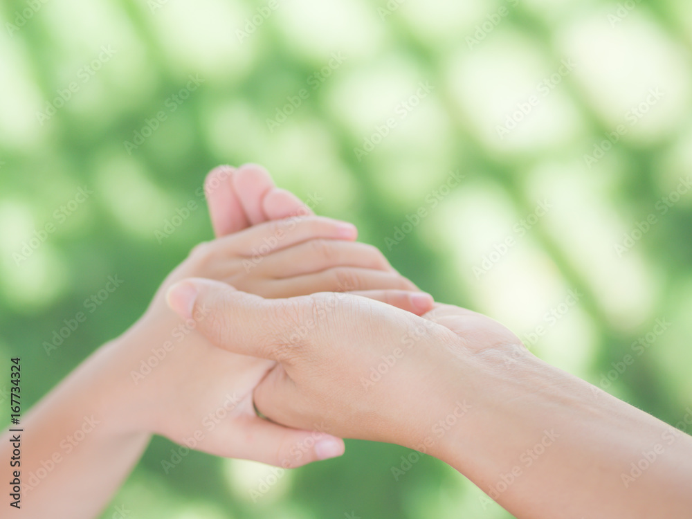 close up of woman holds the hand of a lovely child. Mother and son holding hands in the background of the green field. People, charity and family concept. close up of woman holds the hand of a lovely child. Mother and son holding hands in the background of the green field. People, charity and family concept.