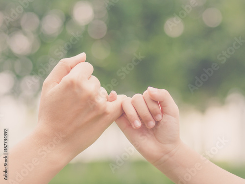 Retro style of mother holding a hand of her kid in spring day outdoors with green field background