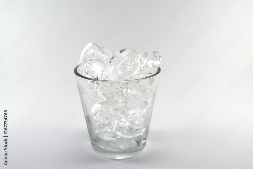 Ice cube in the glass over the white background, soft focus Ice cube in the glass over the white background, soft focus