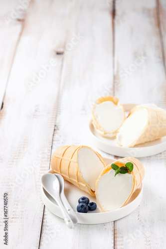 Ice cream in a wafer cup in a plate on a light wooden background. Selective focus. Copy space