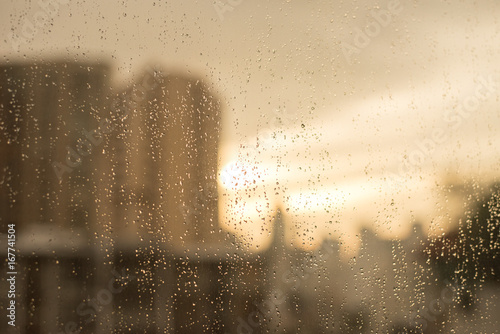 Raindrops on glass window. with blur buildings and warm tone