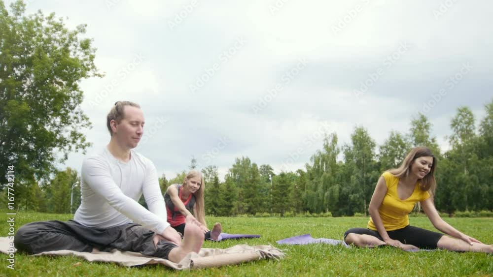 Yoga training in park - young sportsmen performs flexibility exercise outdoor Yoga training in park - young sportsmen performs flexibility exercise outdoor