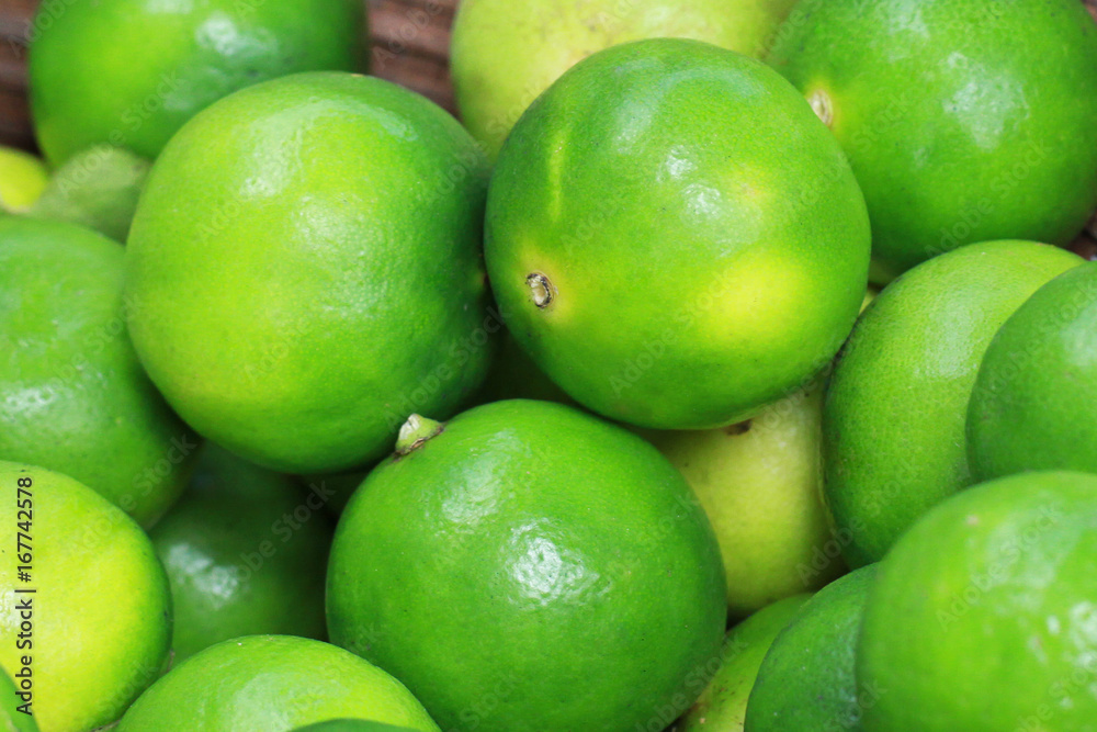 group of Fresh organic green lime Citrus lemon in wooden tray, at fresh market on asian fruit section group of Fresh organic green lime Citrus lemon in wooden tray, at fresh market on asian fruit section