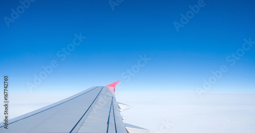 Wing of an airplane flying above the clouds.
