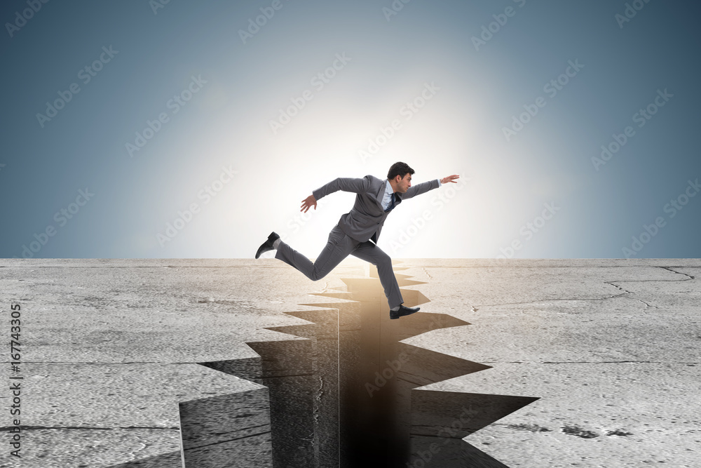 Businessman jumping over the cliff