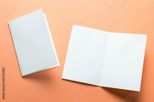 Blank square two-leaf brochures isolated on orange background. Space for text.