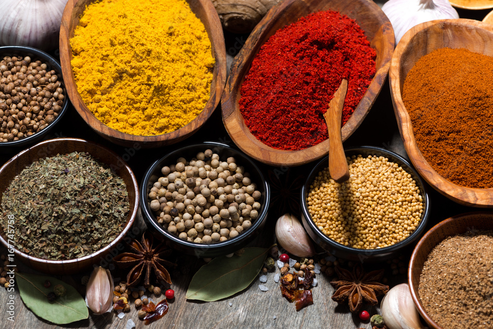 assortment of spices on a wooden background, top view closeup