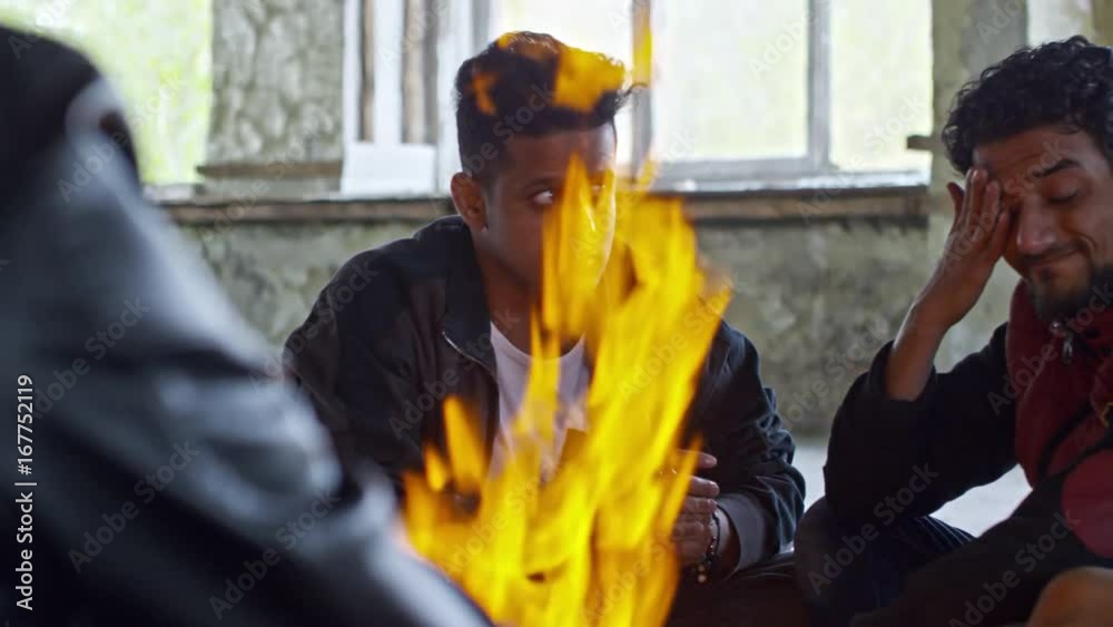 PAN of serious Arab men sitting by fire in abandoned building and thinking PAN of serious Arab men sitting by fire in abandoned building and thinking