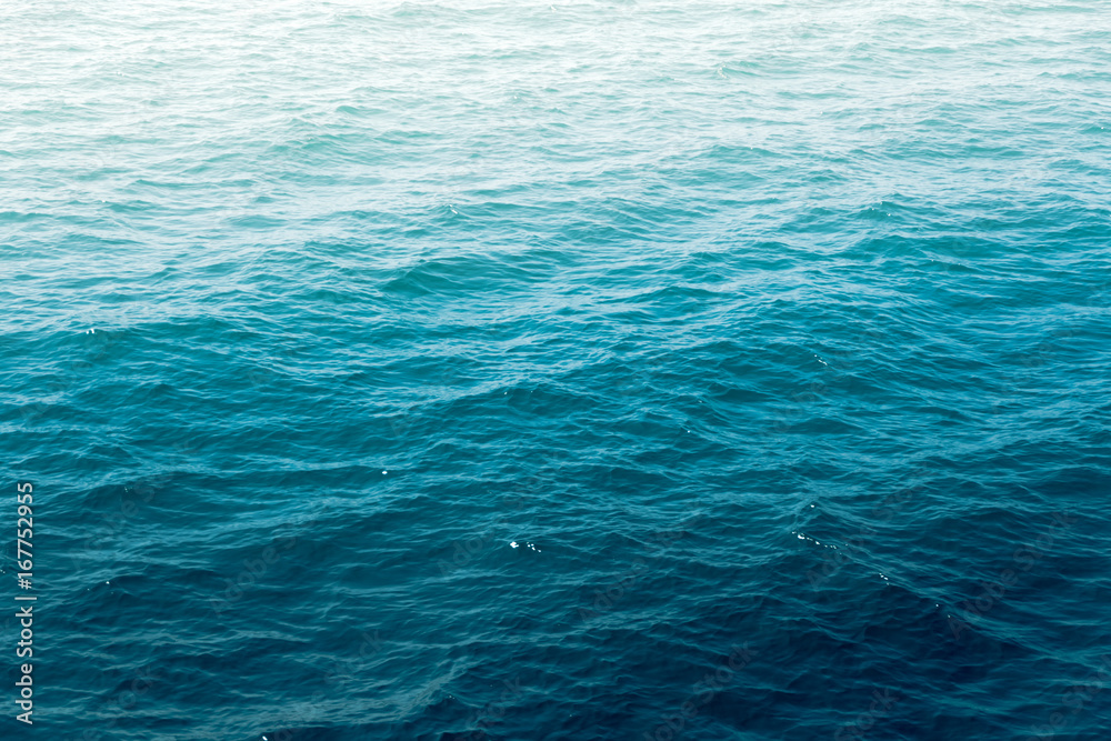 Deep blue sea water wave suface with sun reflection.