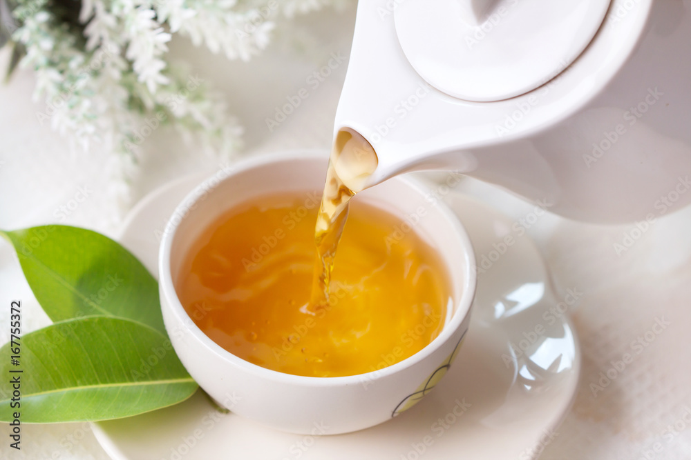 Close up pouring hot black tea in a white tea cup , Tea ceremony time concept Close up pouring hot black tea in a white tea cup , Tea ceremony time concept