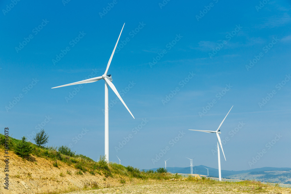 Wind turbines standing on a heels among fields Wind turbines standing on a heels among fields