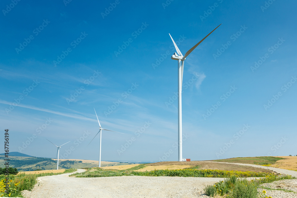 Wind turbines standing on a heels among fields Wind turbines standing on a heels among fields