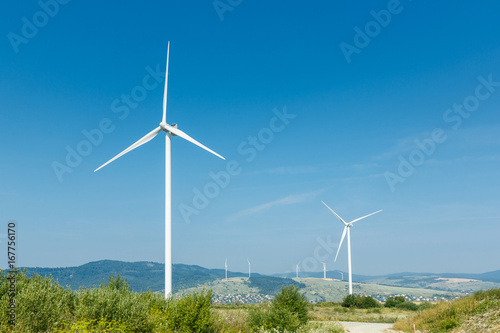 Wind turbines standing on a heels among fields