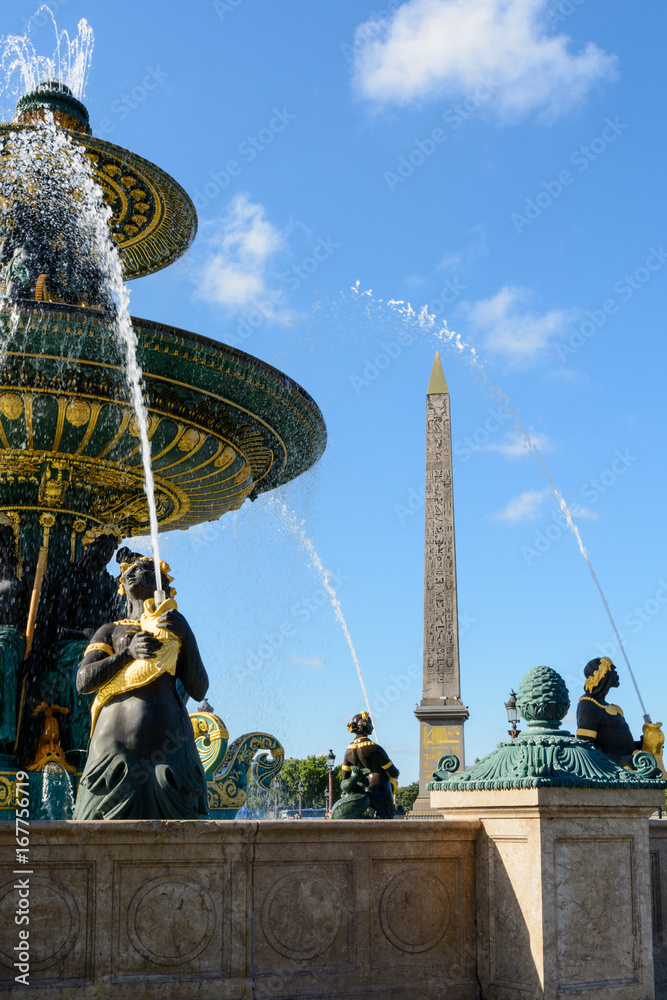 The Fountain of the Rivers in the Concorde square in Paris, France, with Nereids and Tritons holding golden fishes spitting water to the upper basin, and the obelisk of Luxor in the background.