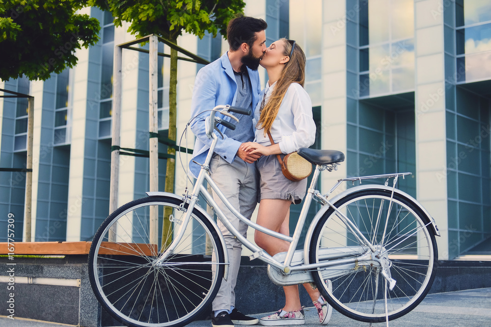 Fototapeta premium A couple on a date after bicycle ride in a city. A man kissing a woman.