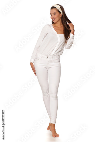 young beautiful woman in white clothes posing barefoot on a white background