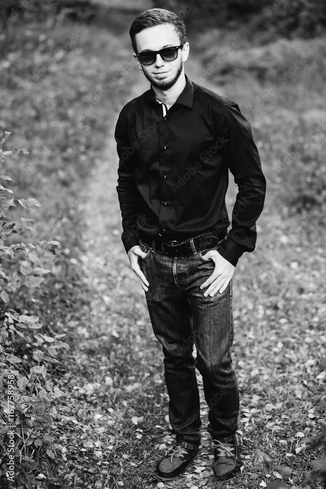 Young elegant man wearing black shirt hold hands in pockets Young elegant man wearing black shirt hold hands in pockets
